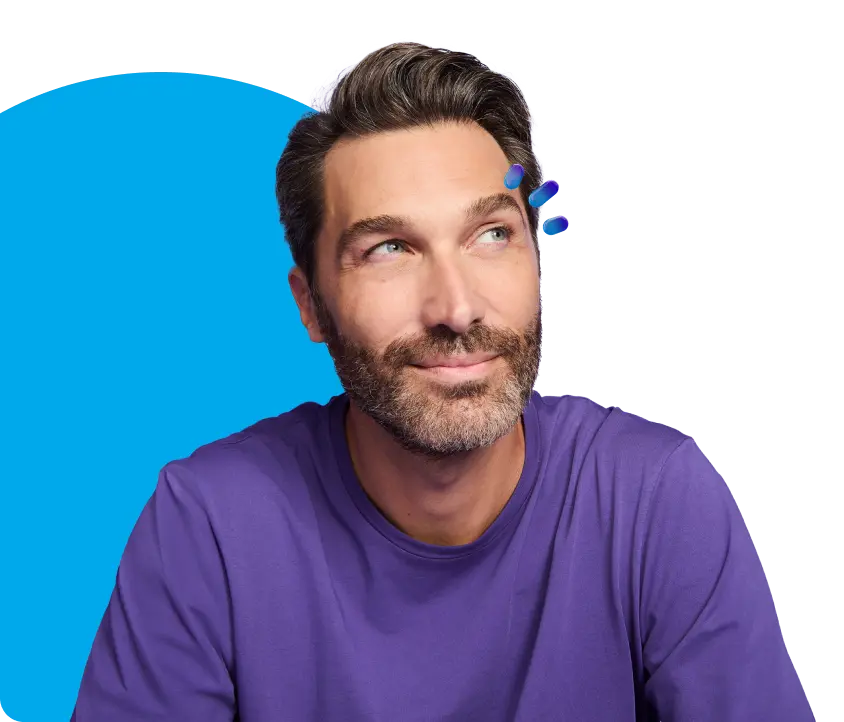 A man in a purple tee shirt smiling with his lips closed while looking off to his left