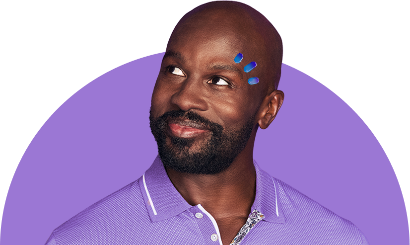 A man in a purple shirt smiling with three drops above his eye
